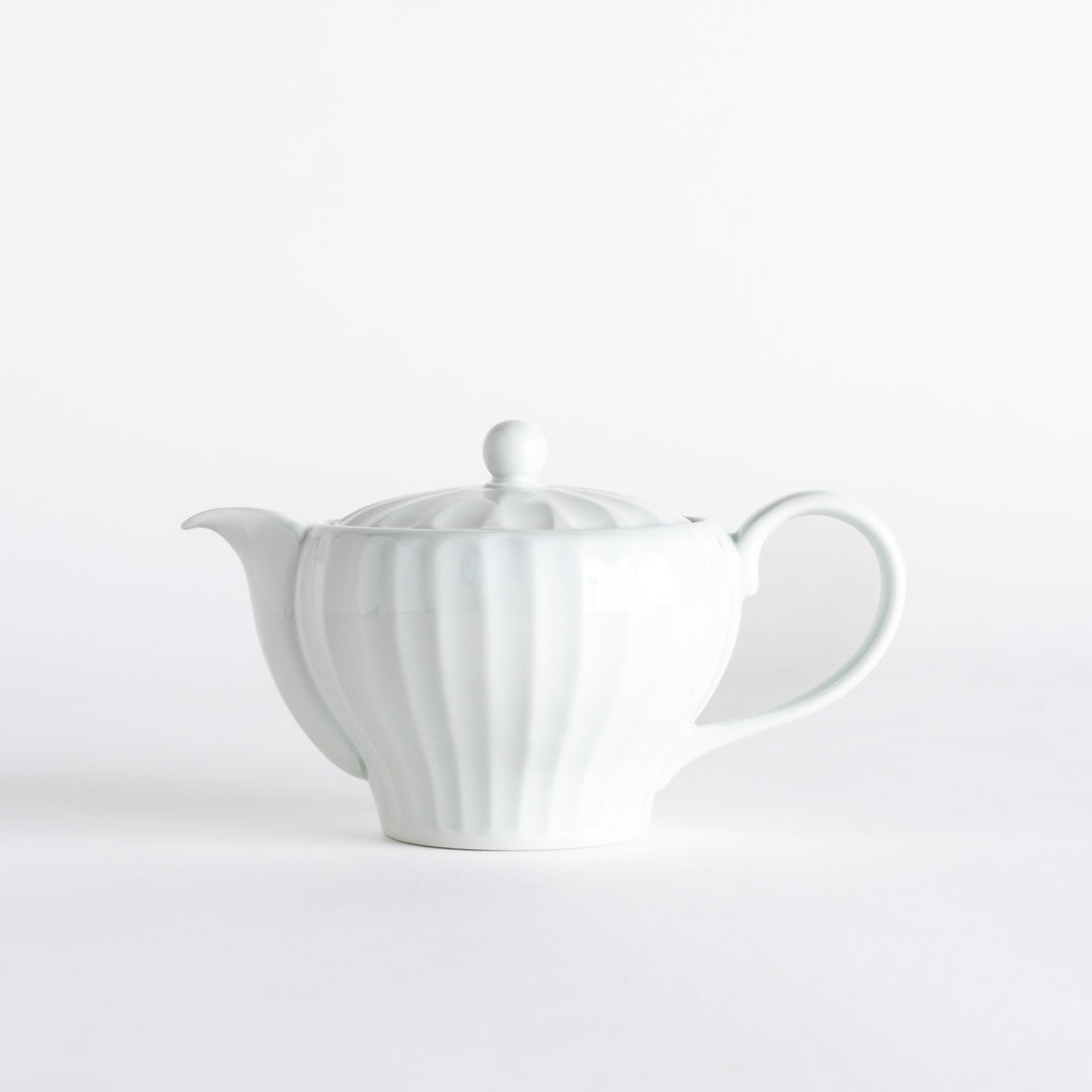 Elegant white teapot with a petal design, showcasing delicate ridges and a rounded spout for stylish tea serving.