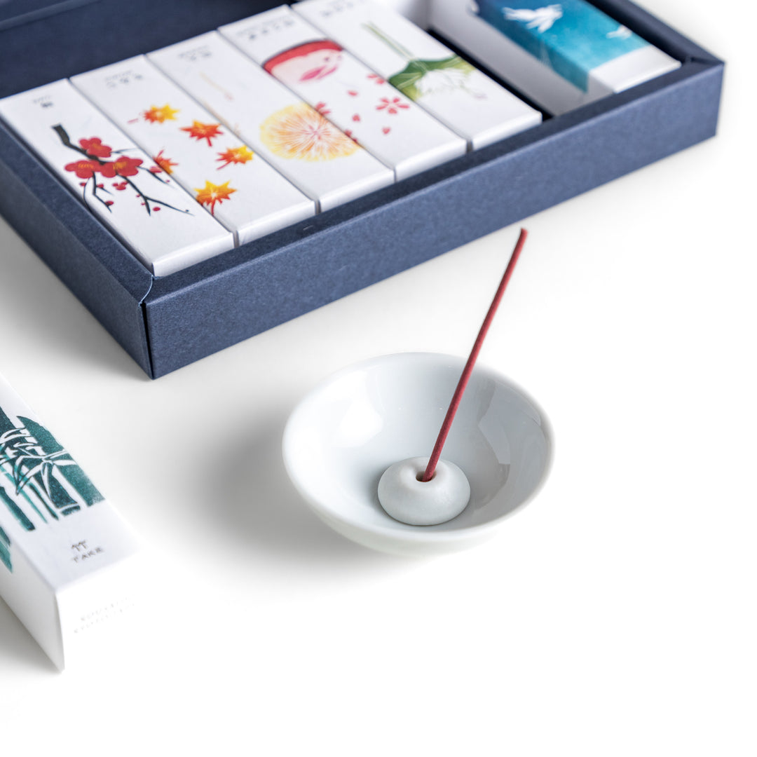 Incense set featuring 10 uniquely designed boxes, each with a different fragrance inspired by nature, along with a ceramic incense holder for an elegant burning experience.