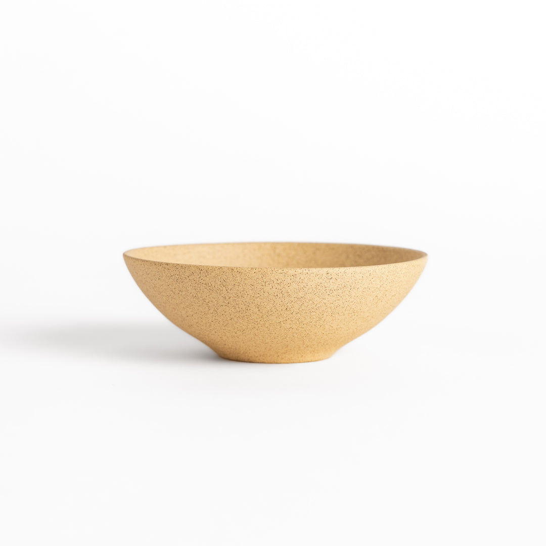 Side view of a beige teacup highlighting its curved shape and minimalist craftsmanship.