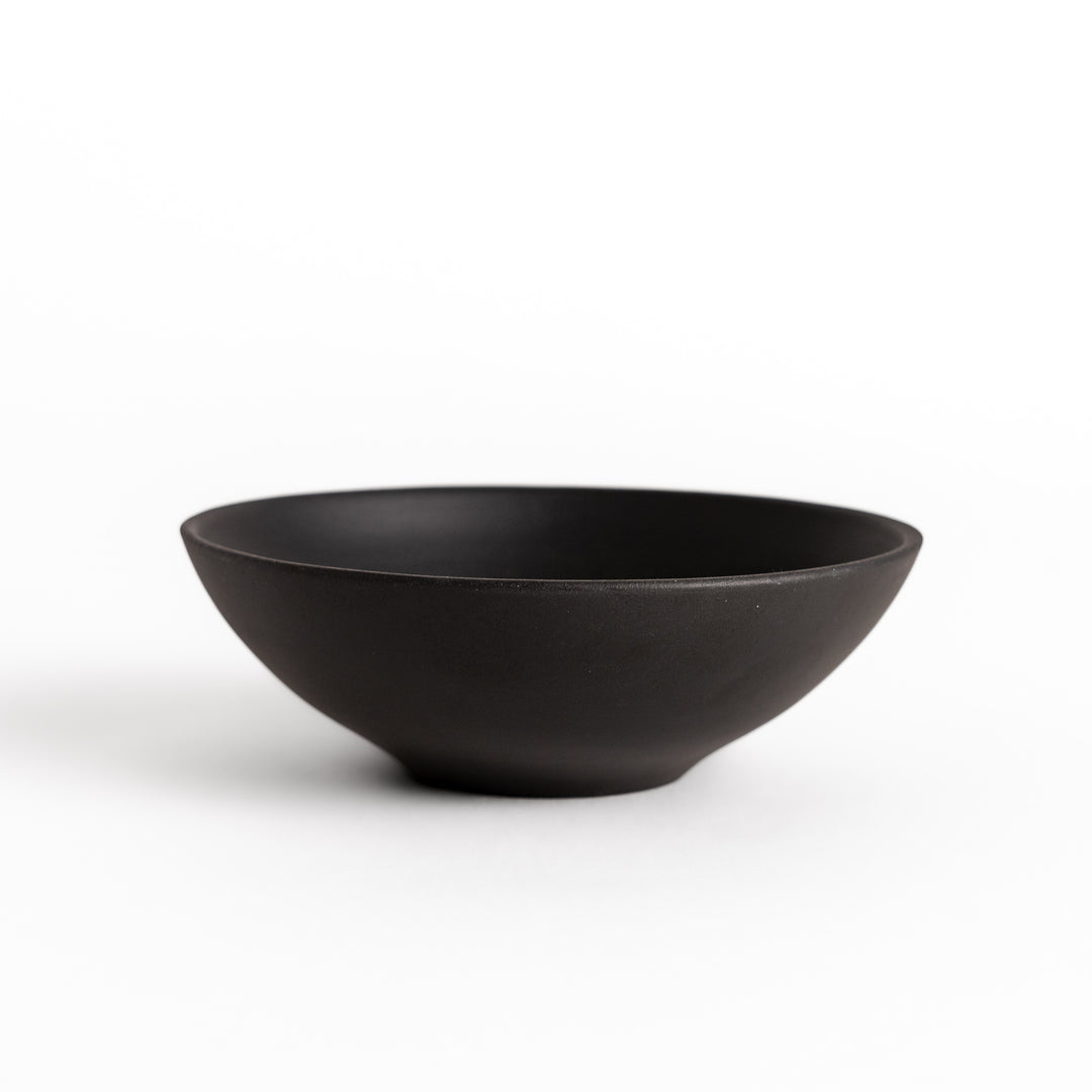 Side view of a black teacup, highlighting its smooth curves and subtle matte texture.