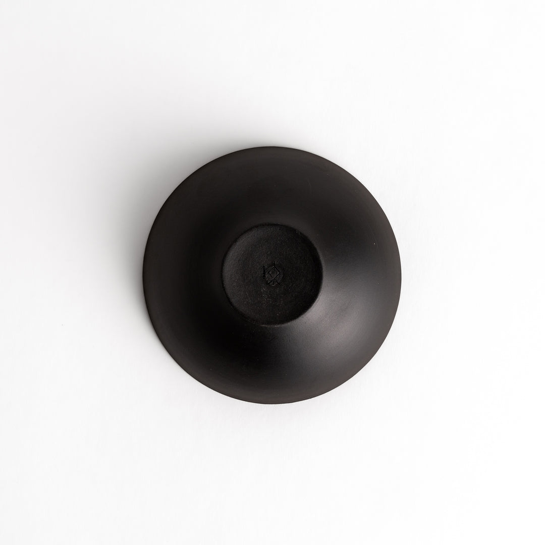 Bottom view of a black teacup, revealing its unglazed base and elegant proportions.