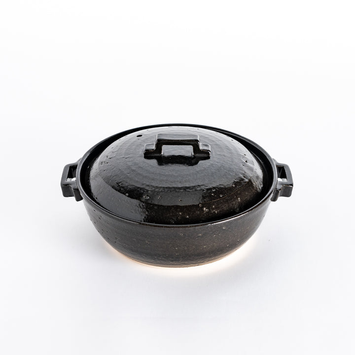 A glossy black donabe pot with a square handle and smooth finish, showcasing its modern design.