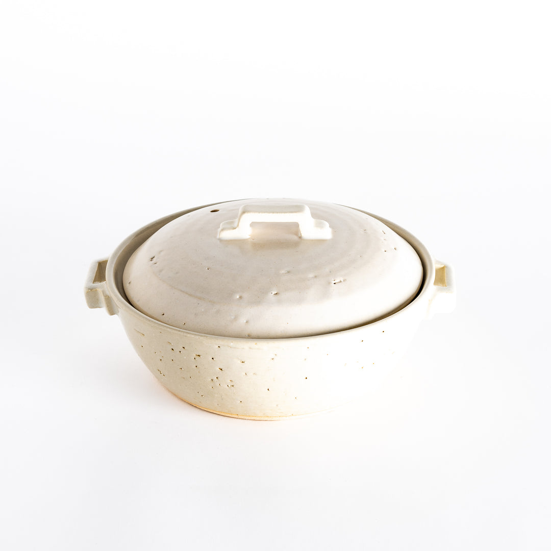 An off-white donabe pot with a subtle speckled finish and square handle, reflecting a simple and elegant style.