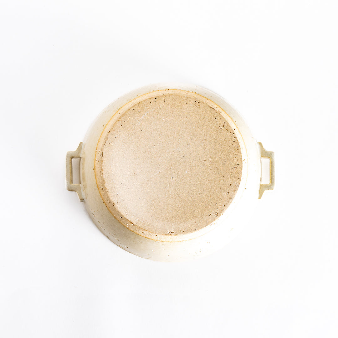 Underside of the off-white donabe pot, featuring subtle speckled details and craftsmanship on the bottom.