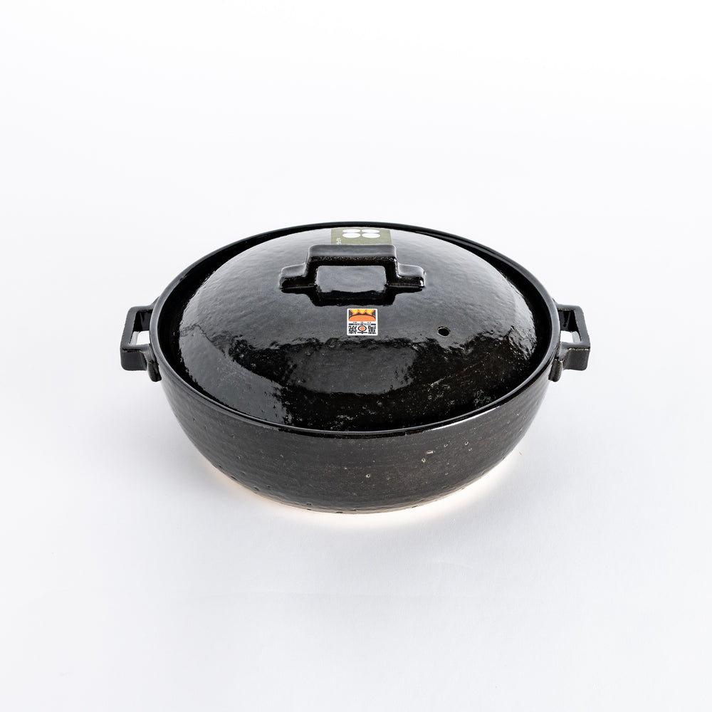 A glossy black donabe pot with a square handle and smooth finish, showcasing its modern design.