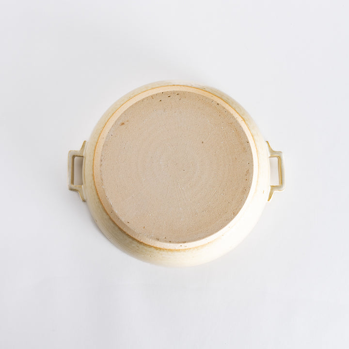 Underside of the off-white donabe pot, featuring subtle speckled details and craftsmanship on the bottom.