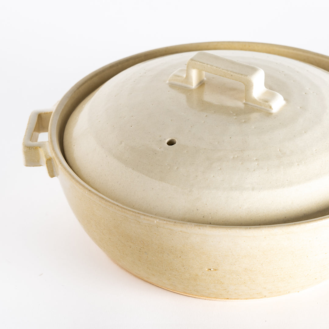 Close-up of the white donabe pot, highlighting its speckled texture and precise craftsmanship near the lid handle.