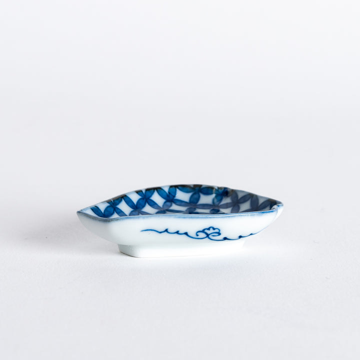 A side view of a blue geometric-patterned sauce dish shaped like a vase, with a delicate wave design along the base.