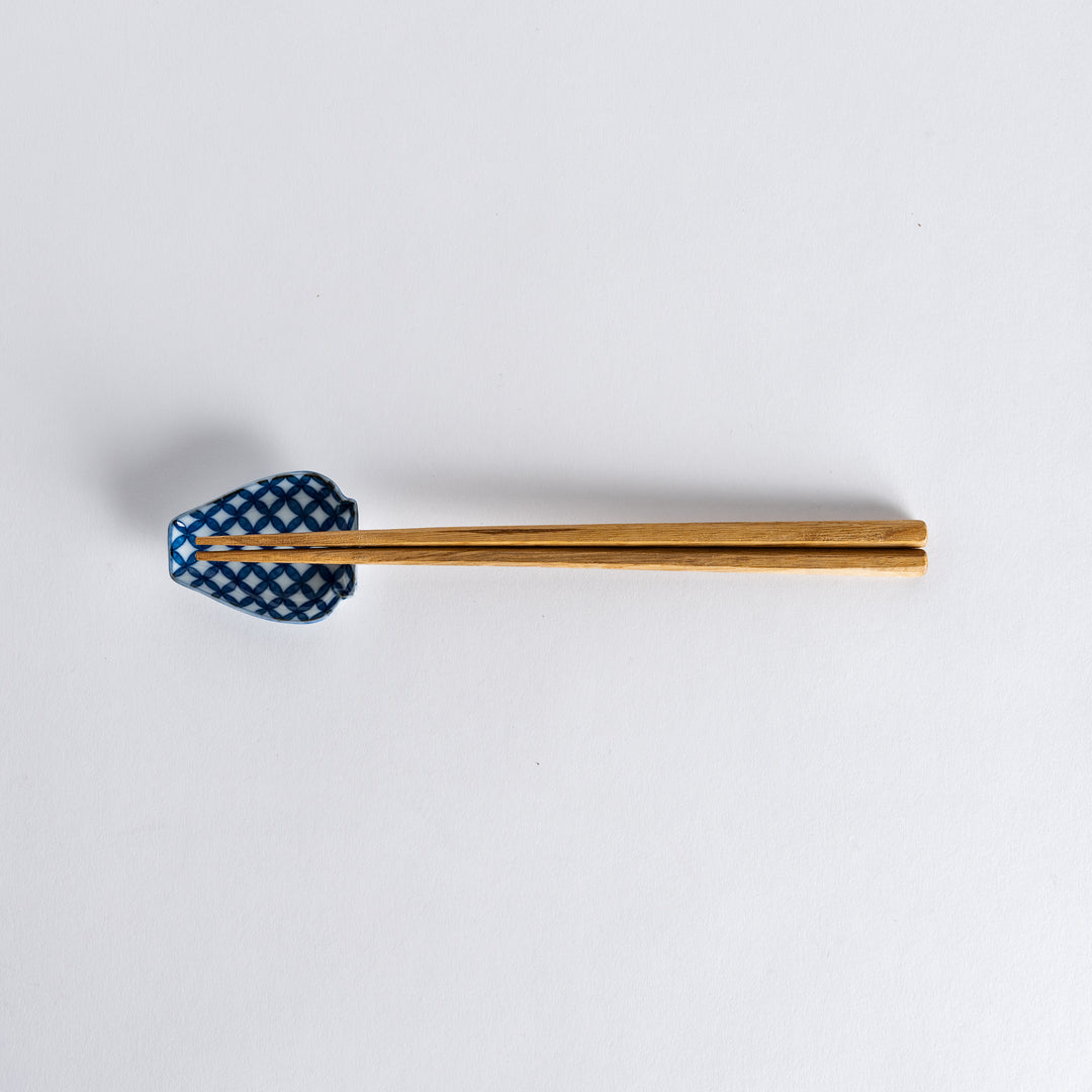 Chopsticks placed on the blue geometric vase-shaped sauce dish with a flower pattern, showcasing its unique design.