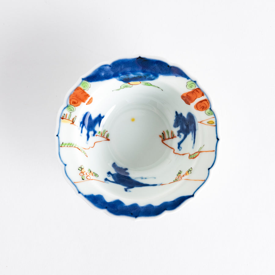 A small dessert bowl featuring colorful designs, including a galloping horse and abstract landscape motifs.