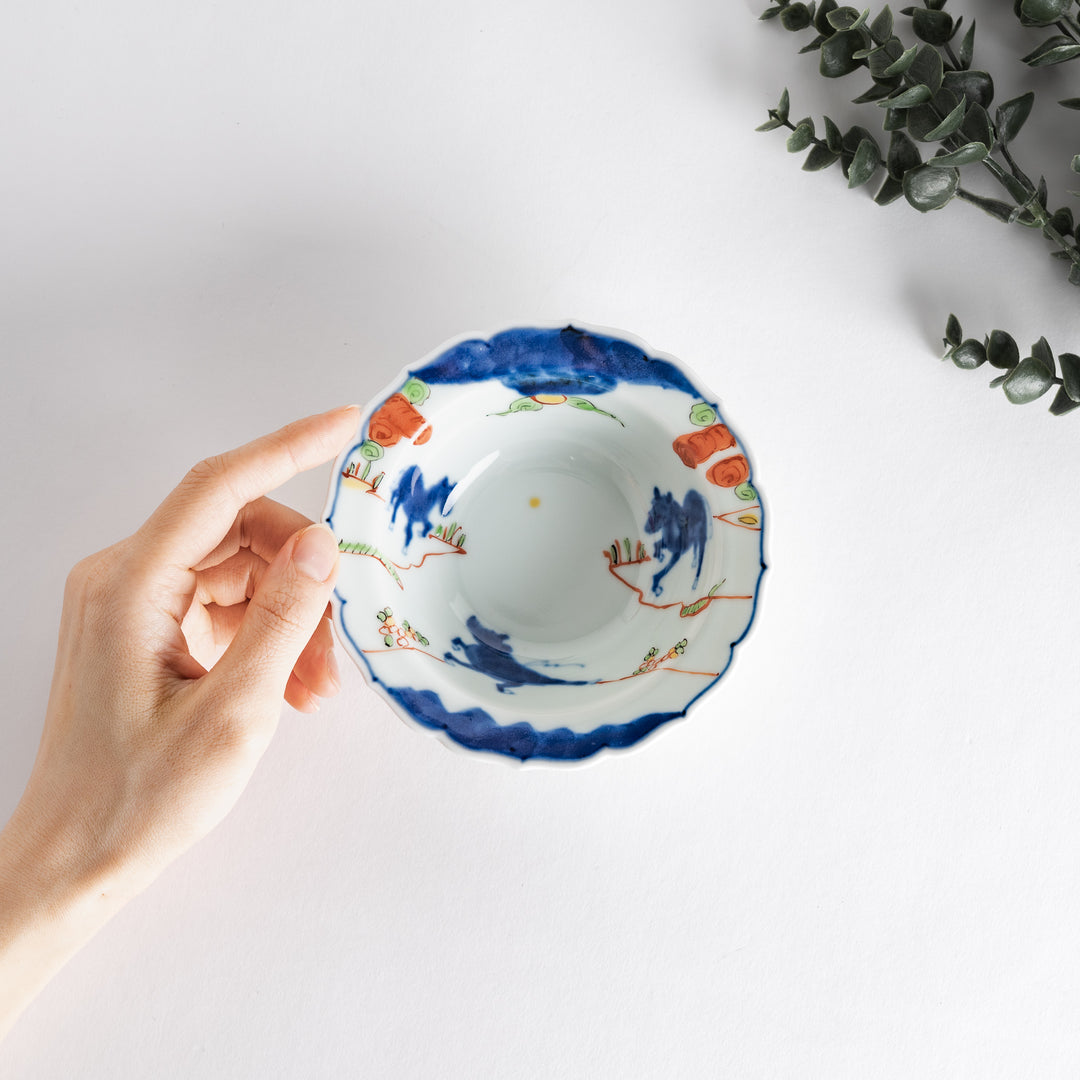 A small dessert bowl featuring colorful designs, including a galloping horse and abstract landscape motifs.