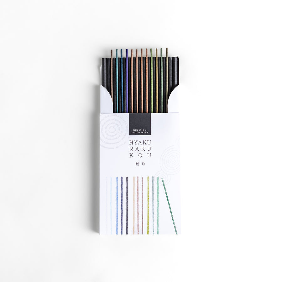 Incense set featuring a variety of colorful sticks elegantly packaged in a sleek white box with subtle circular patterns, offering a refined selection of rich and soothing aromas.