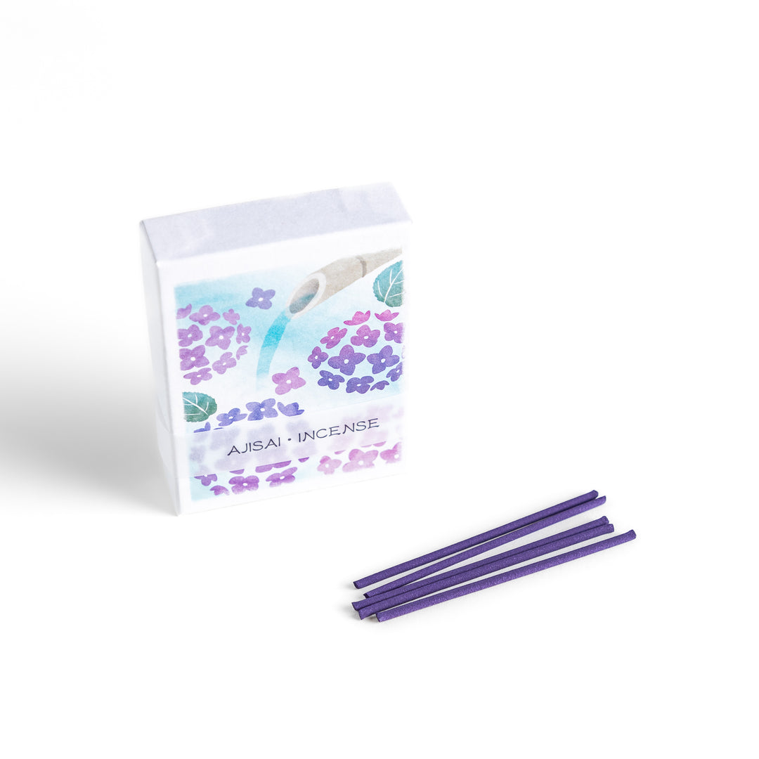 Incense with deep purple sticks, presented in a box adorned with delicate hydrangea flowers and a flowing bamboo spout, offering a serene and refreshing floral fragrance.