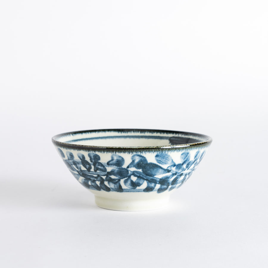 A ceramic ramen bowl with blue arabesque patterns on a white base, slightly flared with a clean, rounded foot.