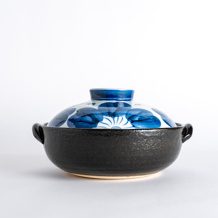 A donabe with a vibrant blue floral pattern lid and black pot.