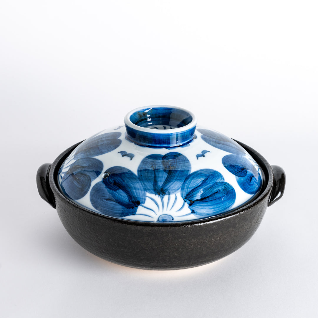 A donabe with a vibrant blue floral pattern lid and black pot.