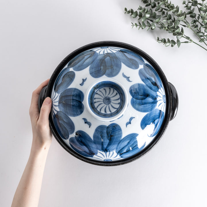 A donabe with a vibrant blue floral pattern lid and black pot.