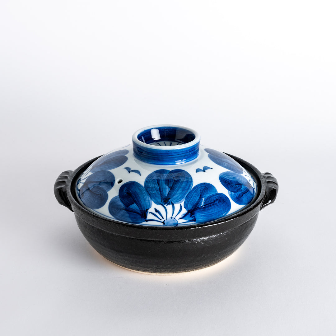 A 8-inch donabe with a vibrant blue floral pattern lid and black pot.