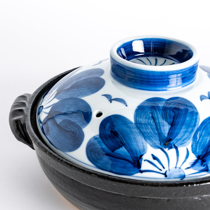 A 8-inch donabe with a vibrant blue floral pattern lid and black pot.