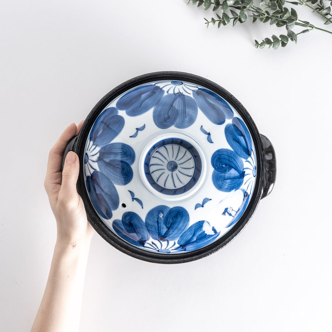 A 8-inch donabe with a vibrant blue floral pattern lid and black pot.