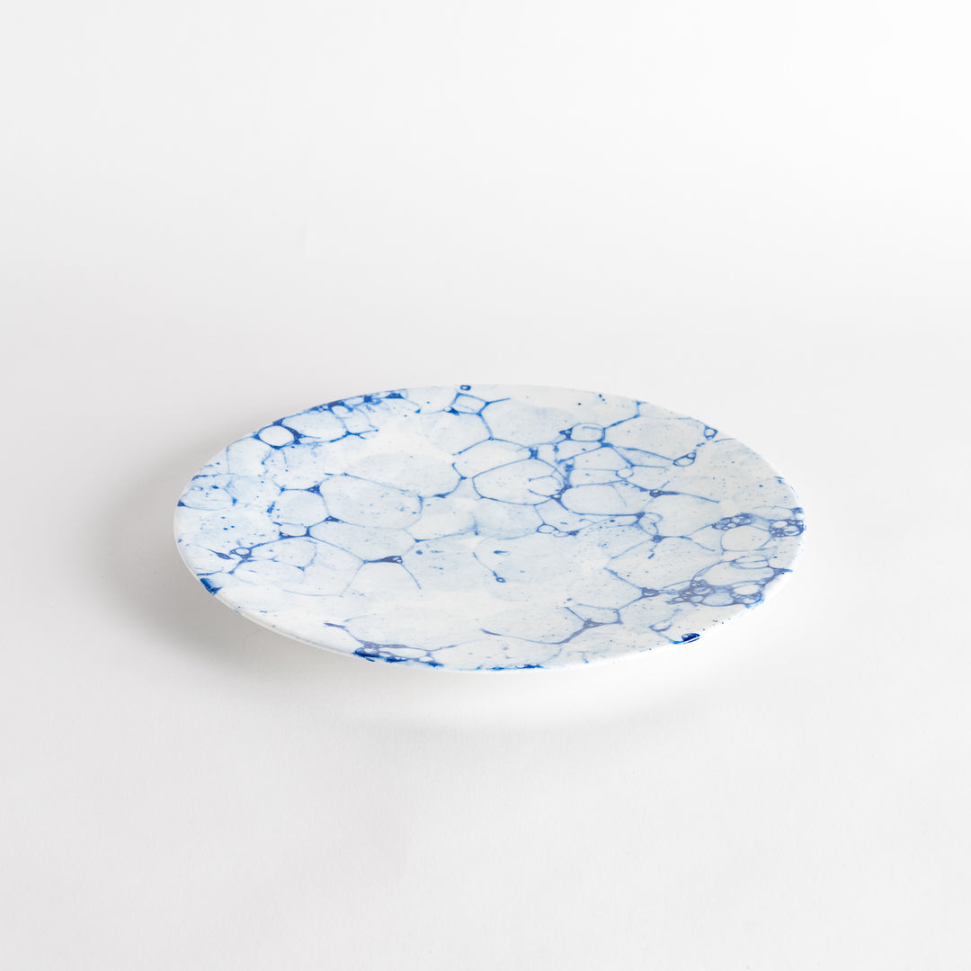 A round dinner plate with a blue bubble-like design on a white background.