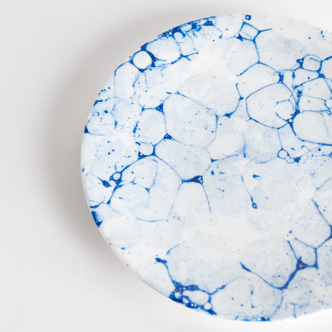 A round dinner plate with a blue bubble-like design on a white background.