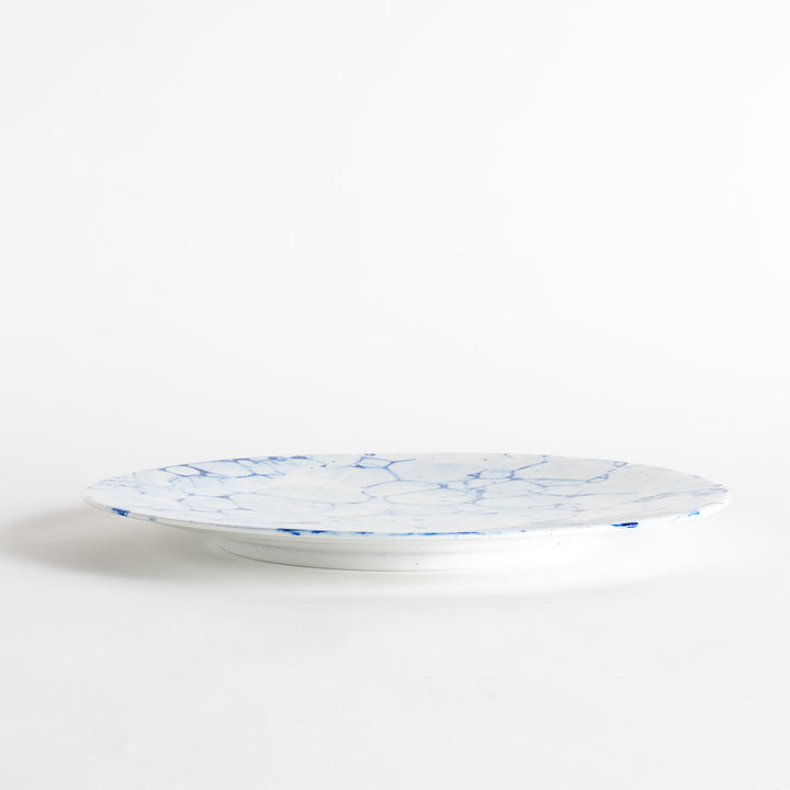 A round dinner plate with a blue bubble-like design on a white background.