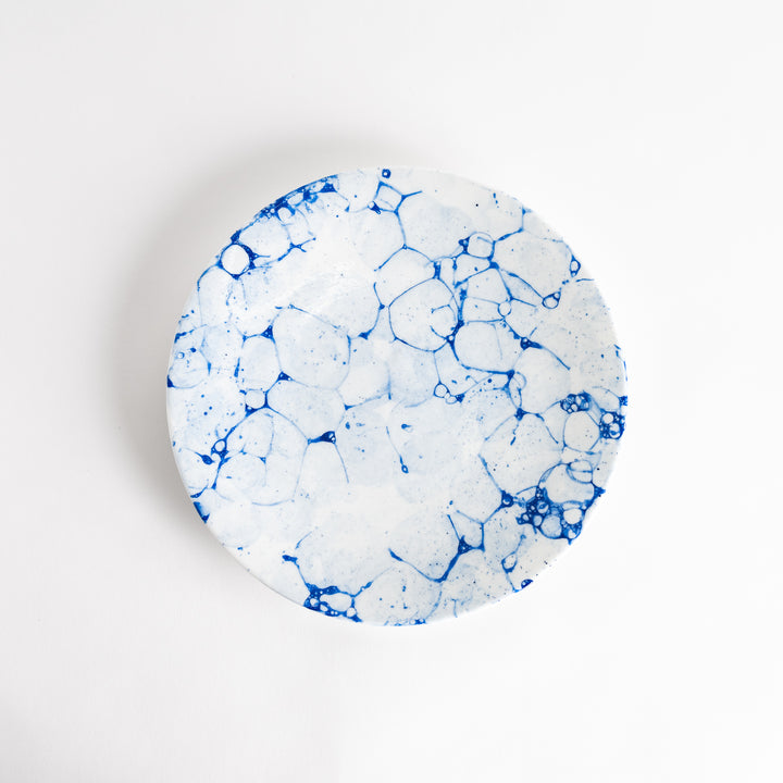 A round dinner plate with a blue bubble-like design on a white background.