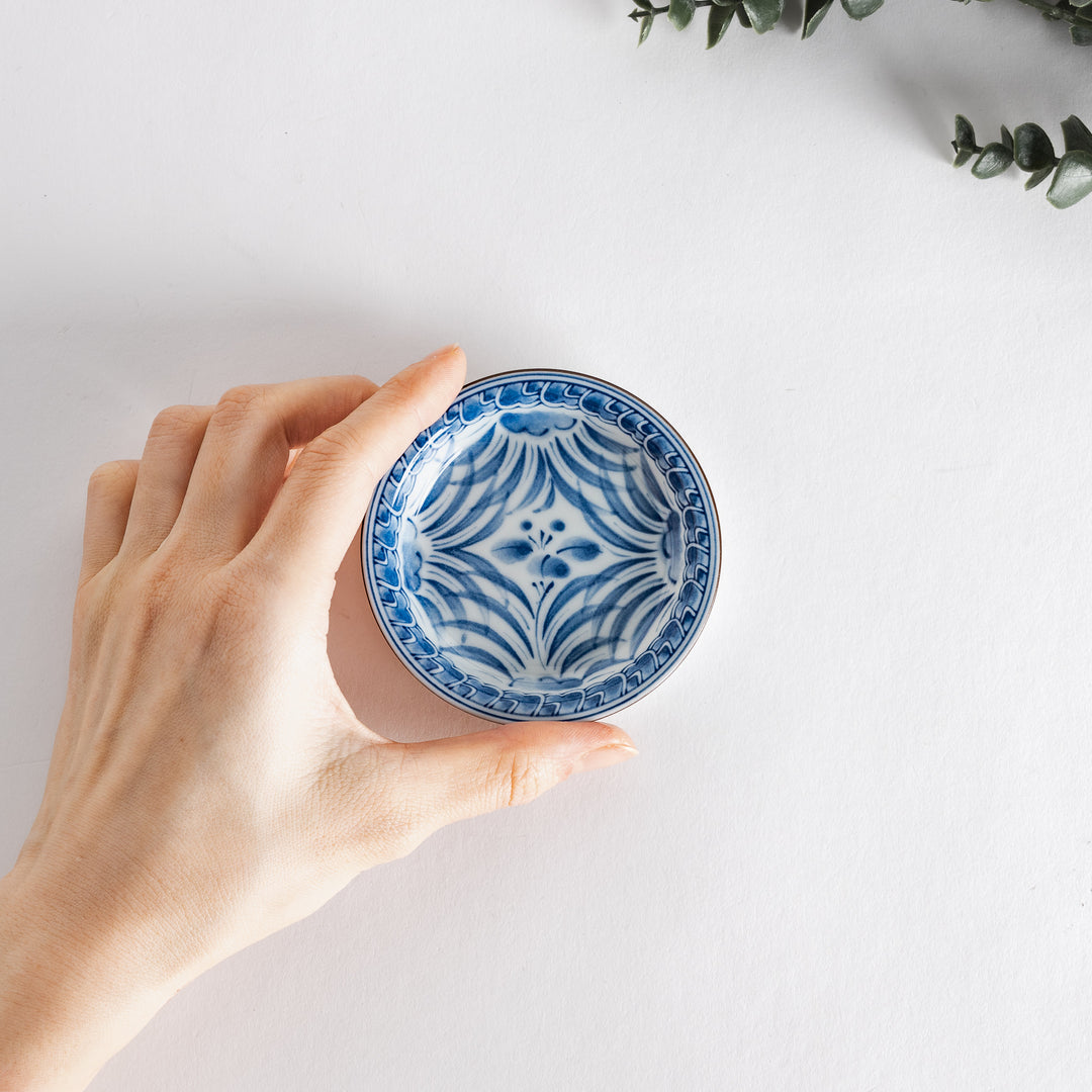 Hand holding the dish, demonstrating its size and the elegance of the design against a neutral background.