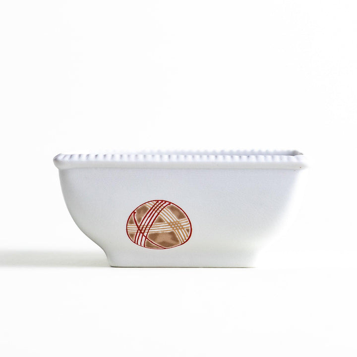 A white square bowl decorated with red and gold circular patterns.