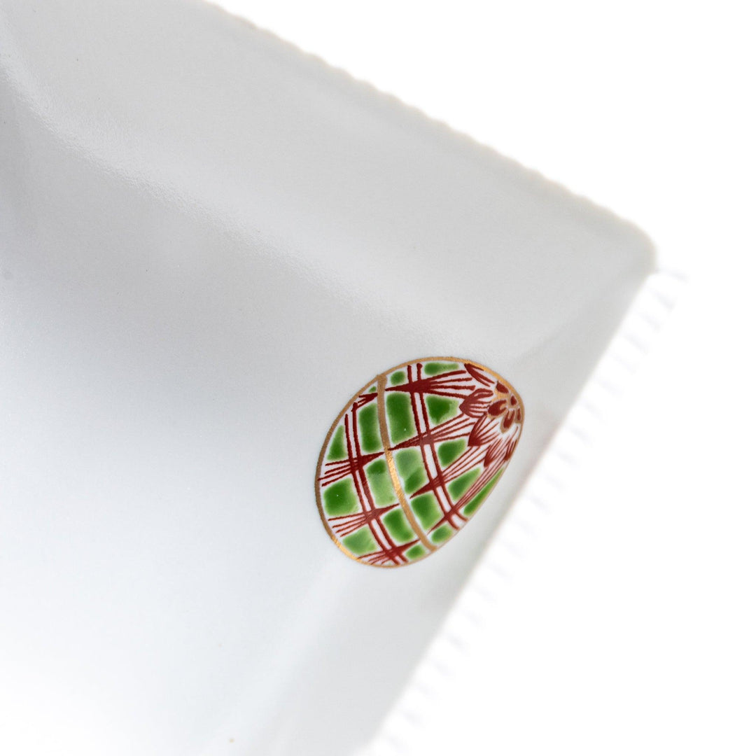 A white square bowl decorated with red and gold circular patterns.