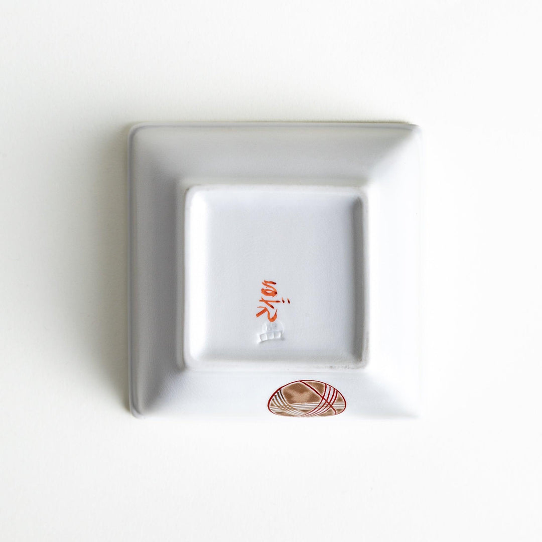 A white square bowl decorated with red and gold circular patterns.