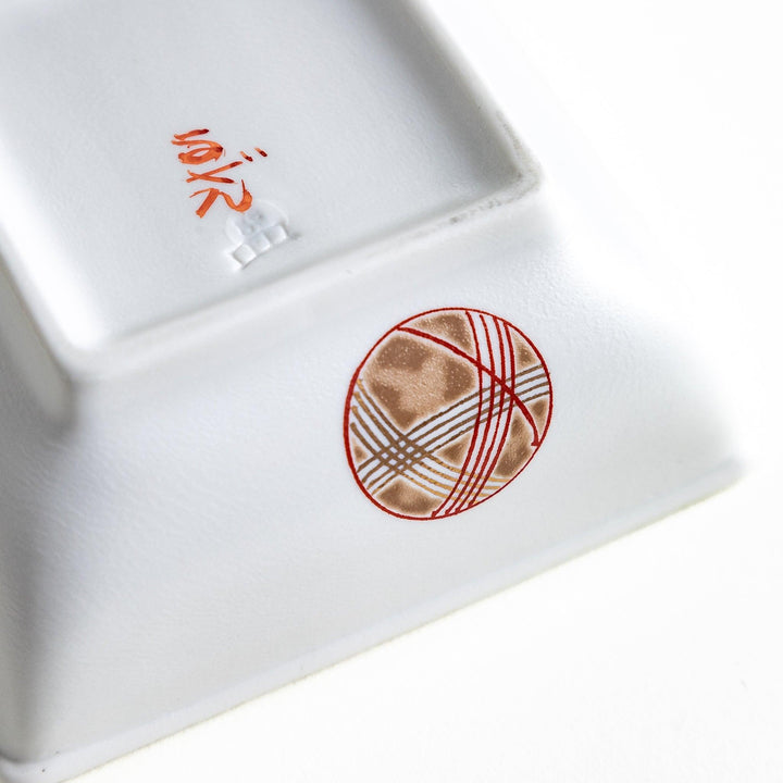 A white square bowl decorated with red and gold circular patterns.