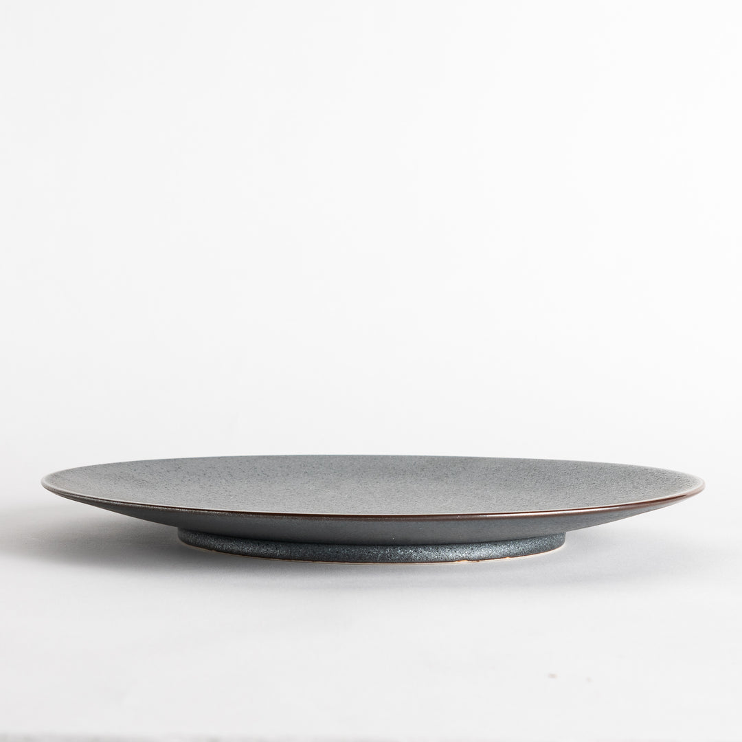 A round, matte black dinner plate with a smooth, understated design.