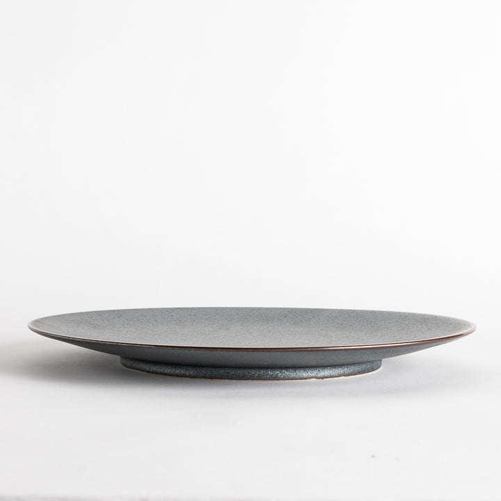 A round, matte black dinner plate with a smooth, understated design.