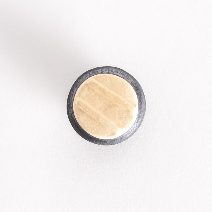 Top-down view of the kamameshi chopsticks rest, showing the beige lid's design and round black base.