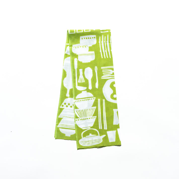 Green tenugui hand towel with white kitchenware patterns, folded neatly to display its vibrant color and intricate design.