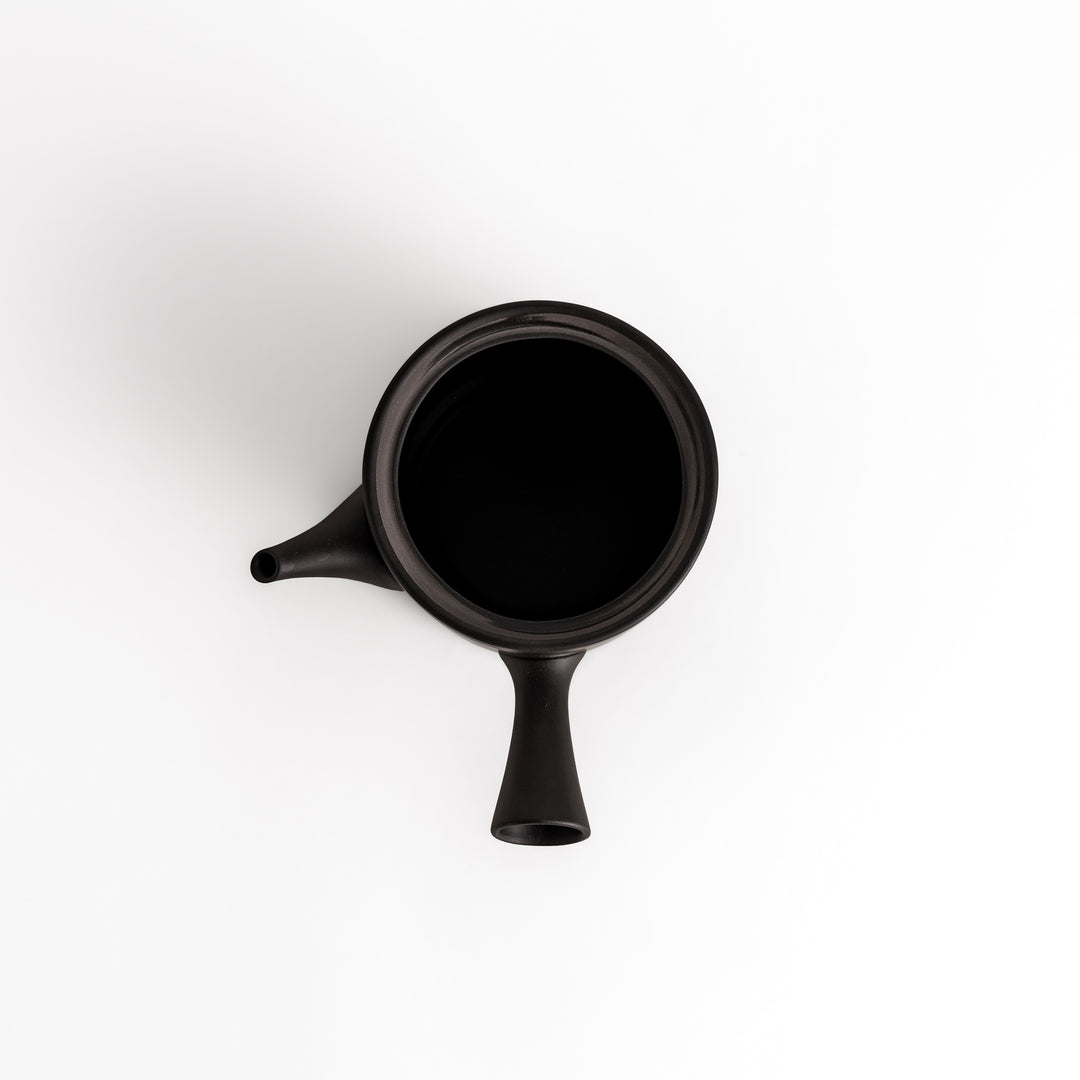 Black teapot with the lid removed, revealing a smooth interior, presented in a clean top-down perspective.