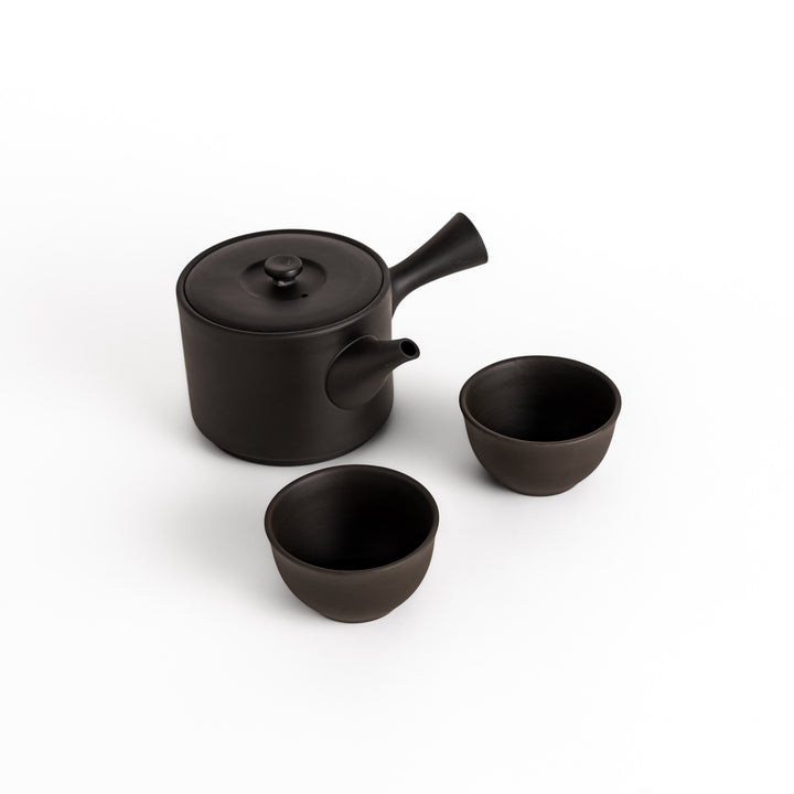 Black teacups paired with a matching teapot, creating a harmonious set for a refined tea-drinking experience.