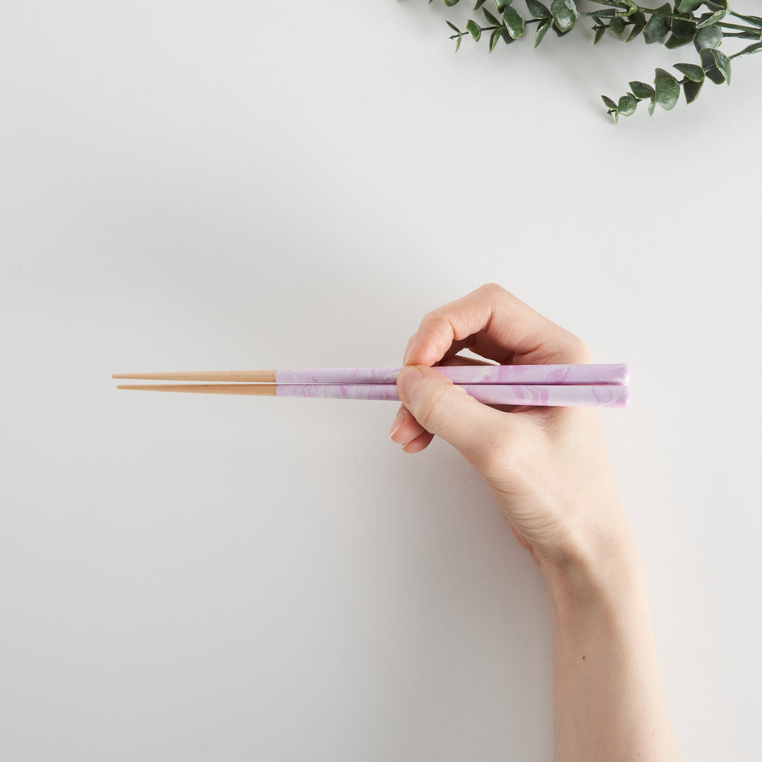 A hand holds the Lavender Breeze Fusion Chopsticks, showcasing the sleek purple design and natural wood.