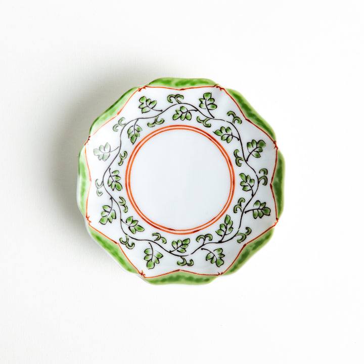 A scalloped porcelain dish with a green and orange leaf pattern encircling the rim, perfect for sauces or small servings.