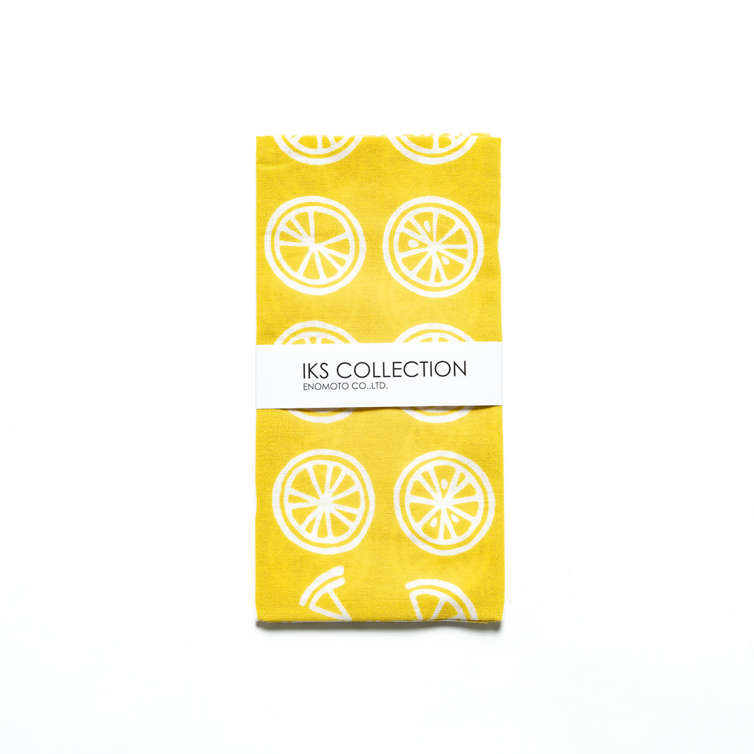 Yellow hand towel with white lemon slice motifs, folded with a branded sleeve.