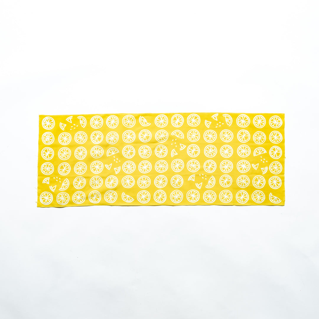 Yellow hand towel featuring white lemon slices, fully spread to showcase its design.