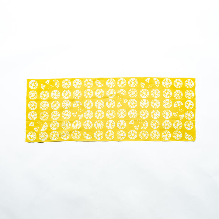 Yellow hand towel featuring white lemon slices, fully spread to showcase its design.