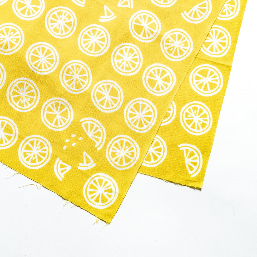 Close-up of white lemon slice patterns on bright yellow hand towel fabric.