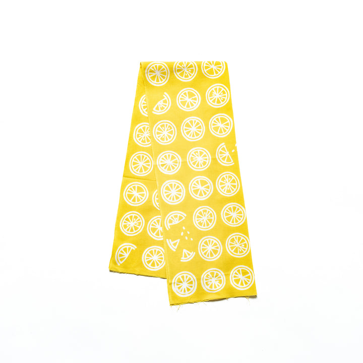 Bright yellow hand towel with white lemon slice patterns neatly folded.