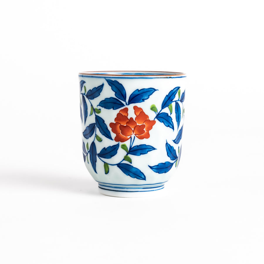 Elegant porcelain teacup with vibrant blue and orange floral design and green leaves, showcasing fine craftsmanship and vivid colors.