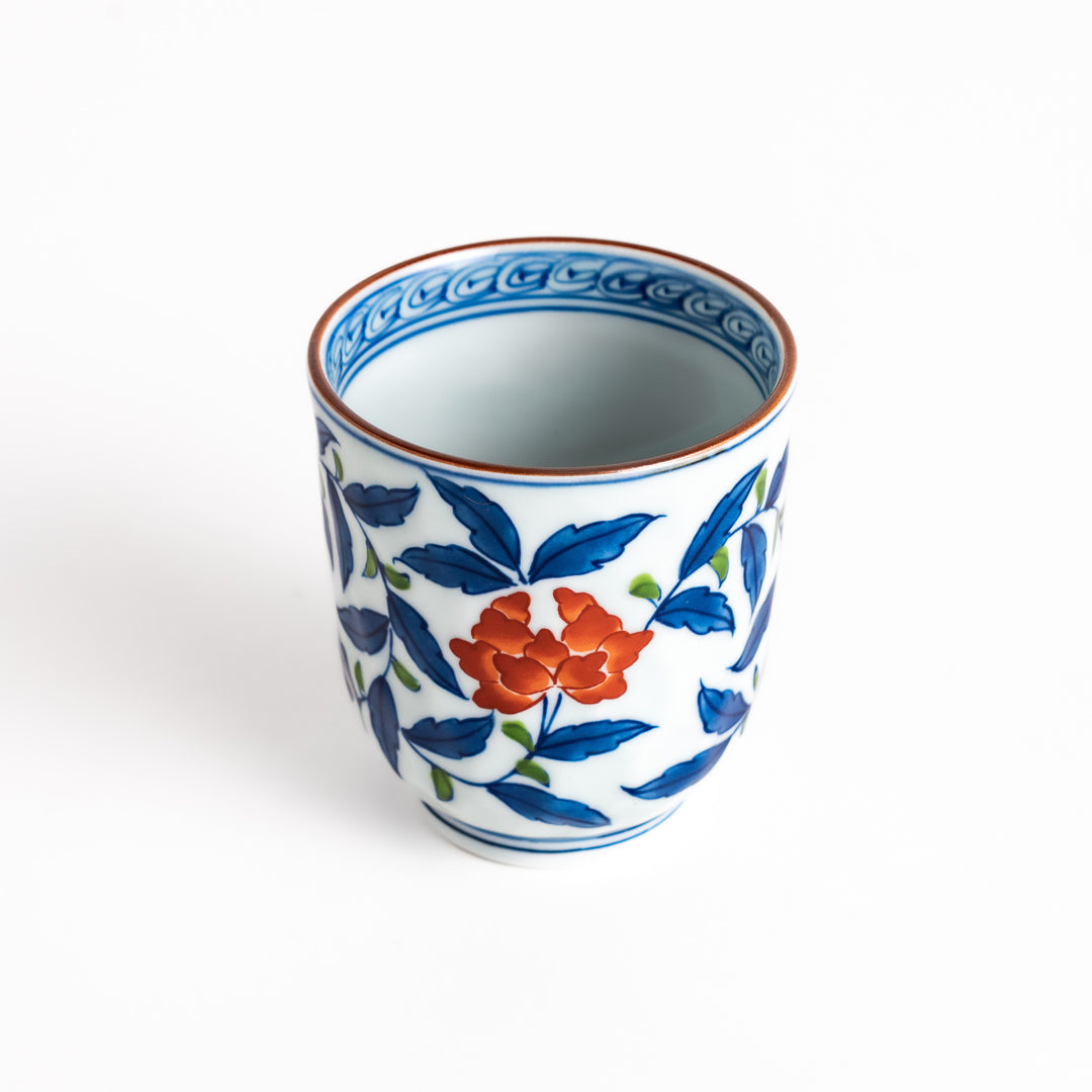 Elegant porcelain teacup with vibrant blue and orange floral design and green leaves, showcasing fine craftsmanship and vivid colors.