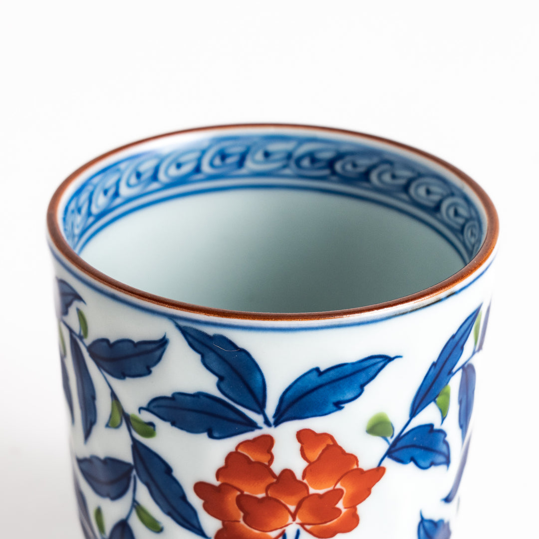 Elegant porcelain teacup with vibrant blue and orange floral design and green leaves, showcasing fine craftsmanship and vivid colors.