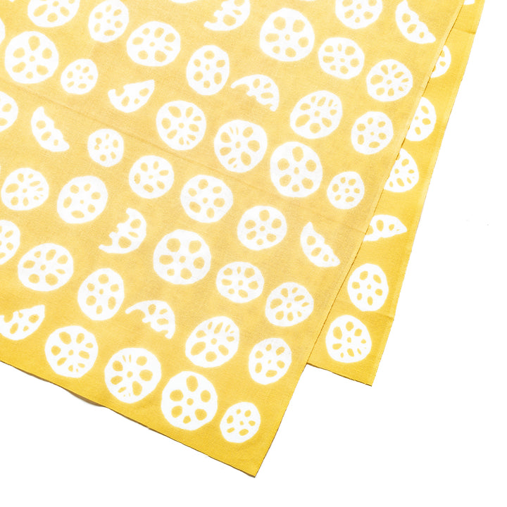 Close-up of white lotus root slice patterns on yellow hand towel fabric.